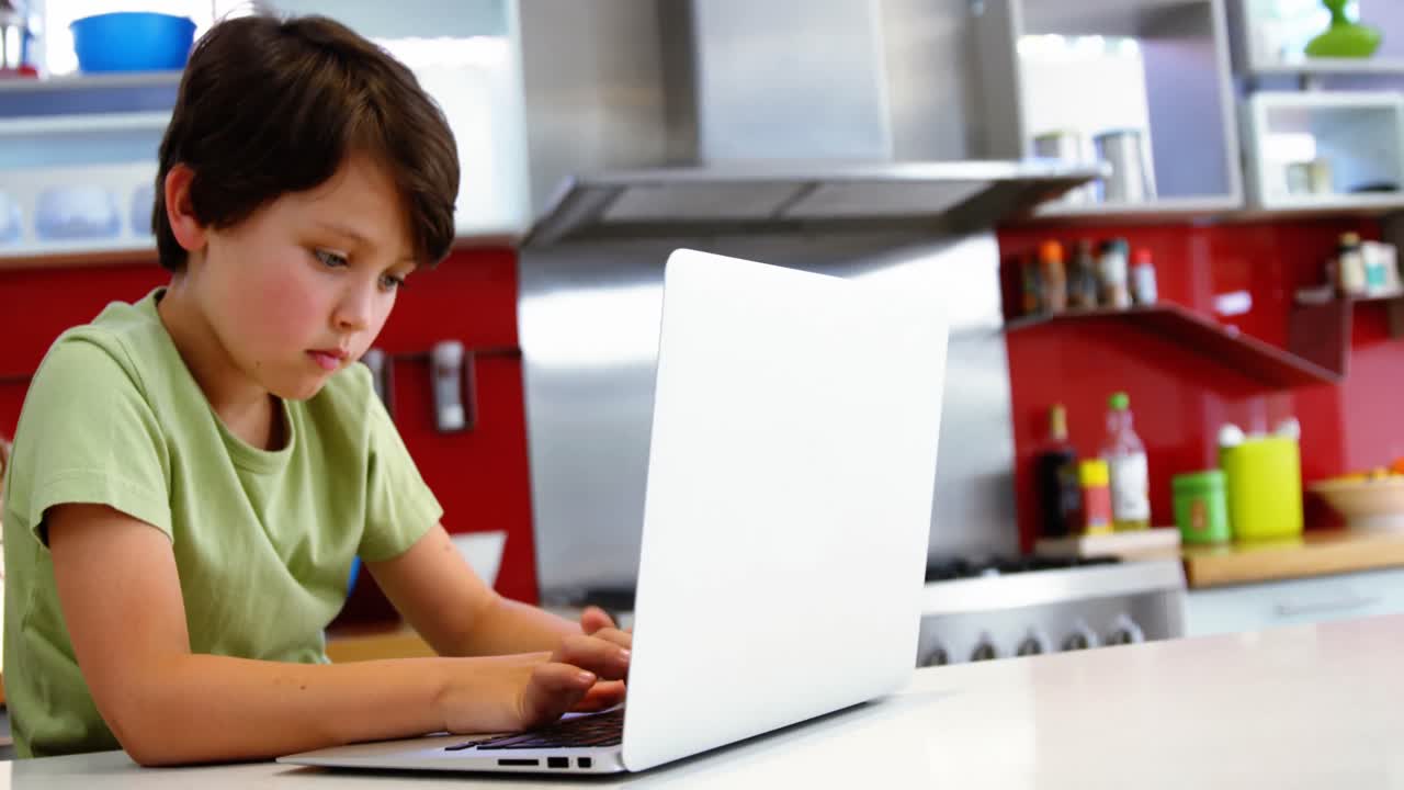 niño usando computadora portátil en la cocina