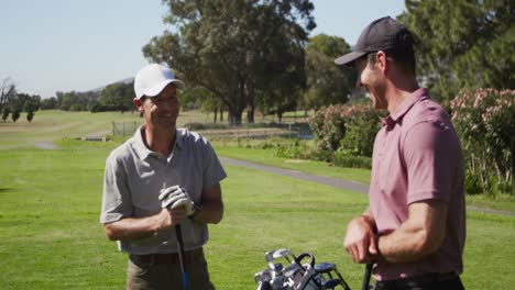 caucasian male golfers talking on a golf course on a sunny day