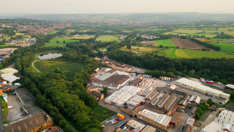 een drone-video van heckmondwike, groot-brittannië, toont industriële structuren, drukke straten en een oud stadscentrum tegen de achtergrond van yorkshire op een zomeravond.