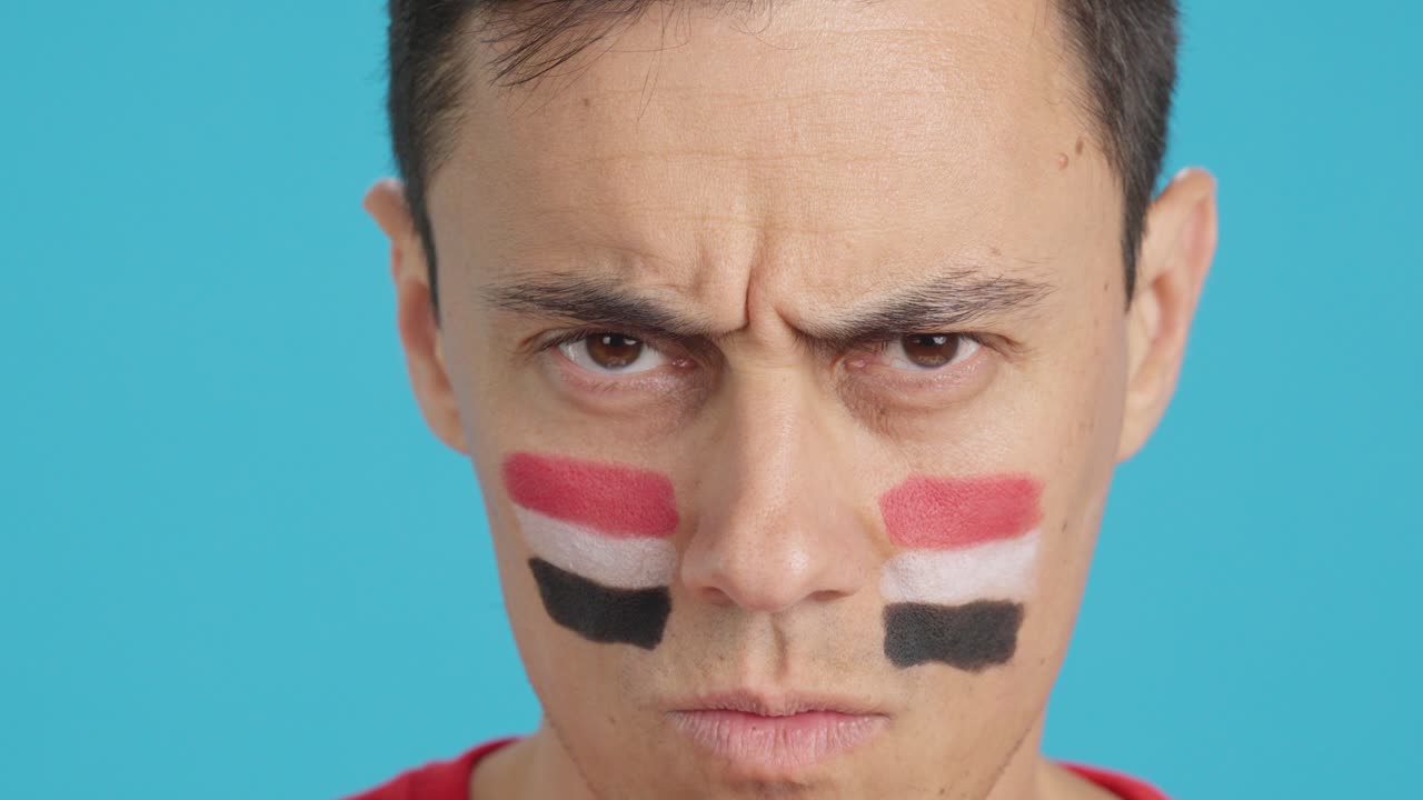 Serious man with a egyptian flag painted on the face