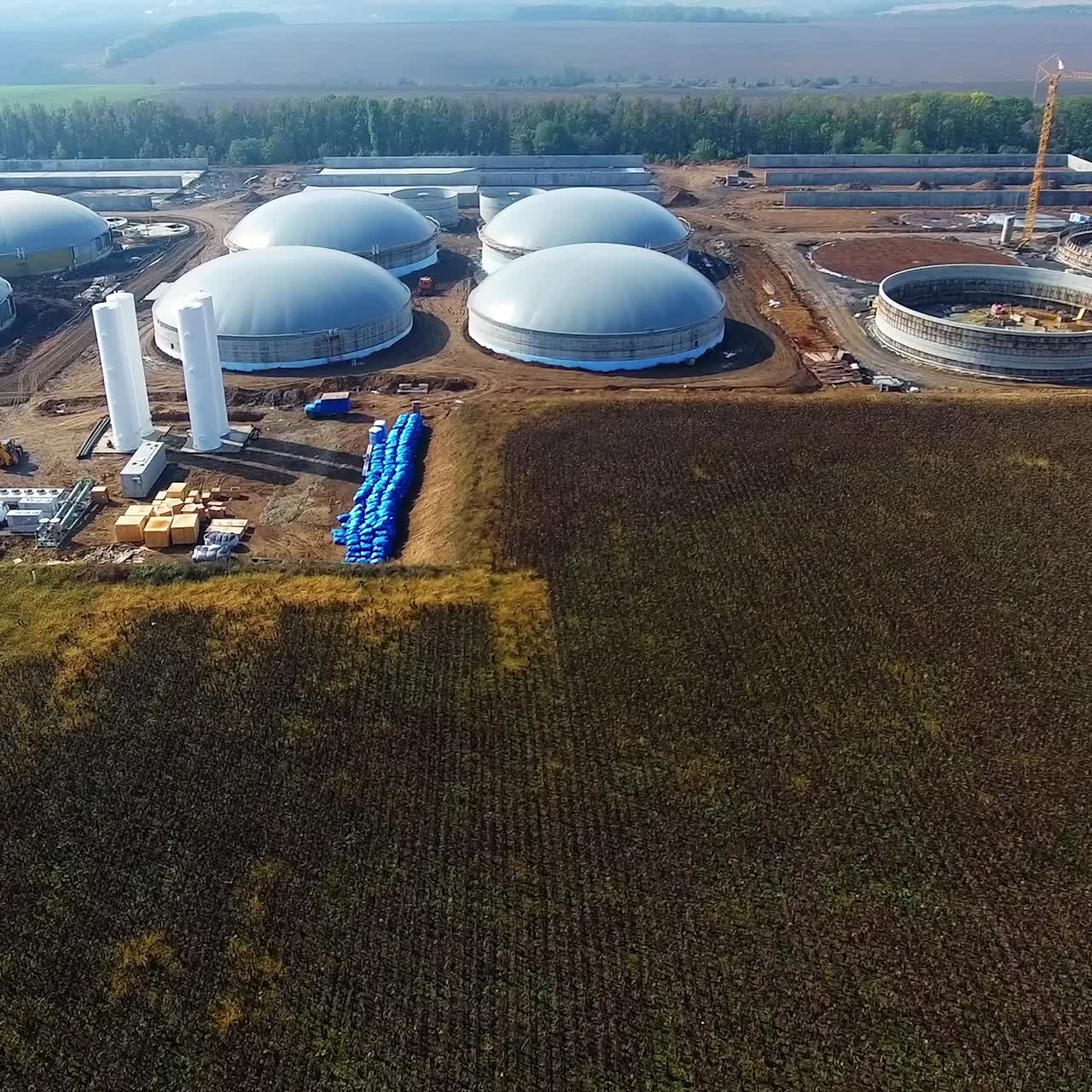Construction of biogas plant on field. Large storage reservoirs for biogas production in environment. Industrial infrastructure among nature. Aerial view.