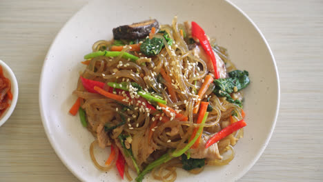 japchae or stir-fried korean vermicelli noodles with vegetables and pork topped with white sesame - korean traditional food style