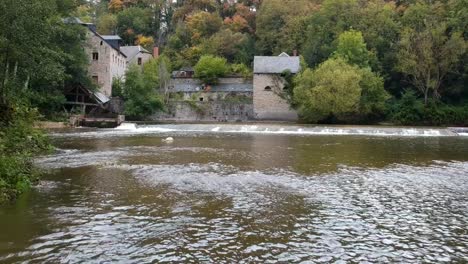 flying over the water of a moat towards an ancient castle at the start of fall with the leaves turning red