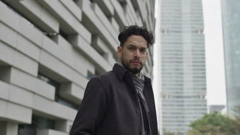 portrait of successful young entrepreneur, dressed in autumn clothes, looking at camera serious and strong, outdoors in downtown business district