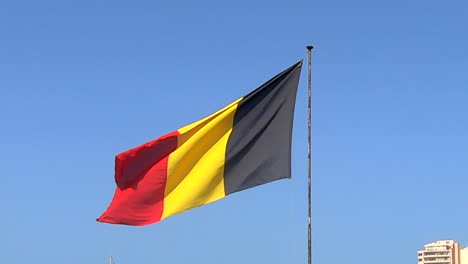 a german flag waving in slow motion on a bright sunny day with the blue sky in the backround.