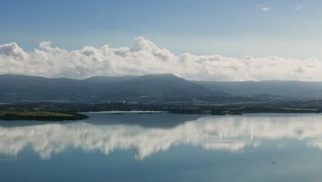 aerial of lake illawarra shoreline with ripples and urban skyline in new south wales, australia, stunning glass reflection