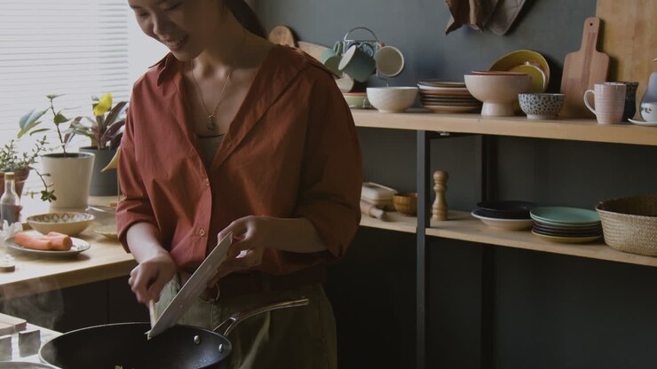 Giovane donna felice che cucina nella sua cucina