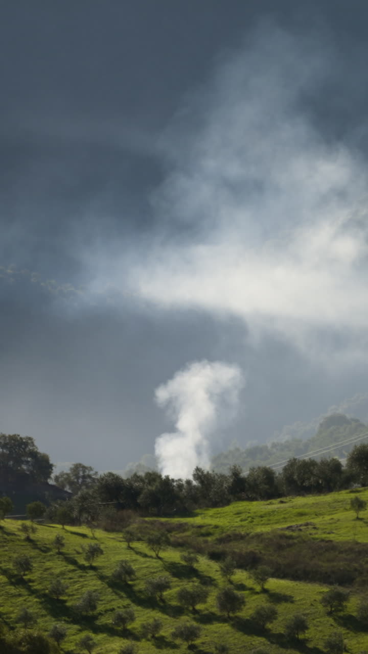 Smoke rising from green misty valley of Spain, static vertical view