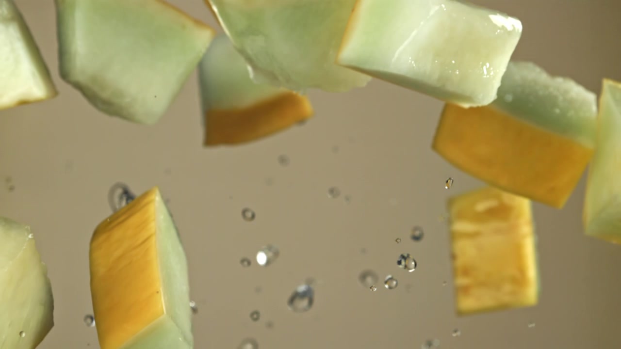 Juicy Melon Pieces Falling in Slow Motion with Water Splashes