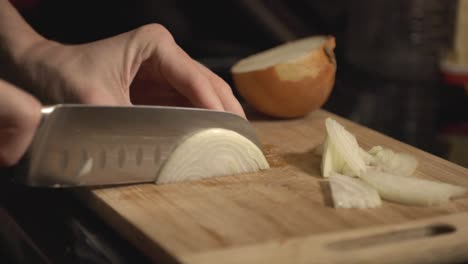 mano del chef cortando cebolla en una tabla de madera