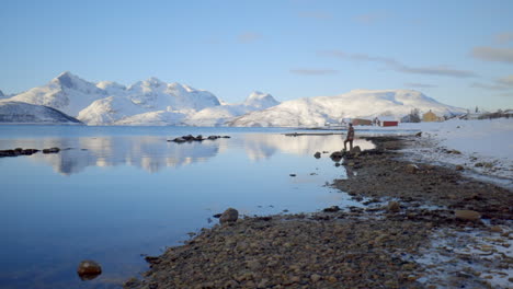 A-Man-Taking-in-a-View-of-Amazing-Winter-Scenery-from-a-Rocky-Shorline-Along-a-Fjord-in-Norway,-Static