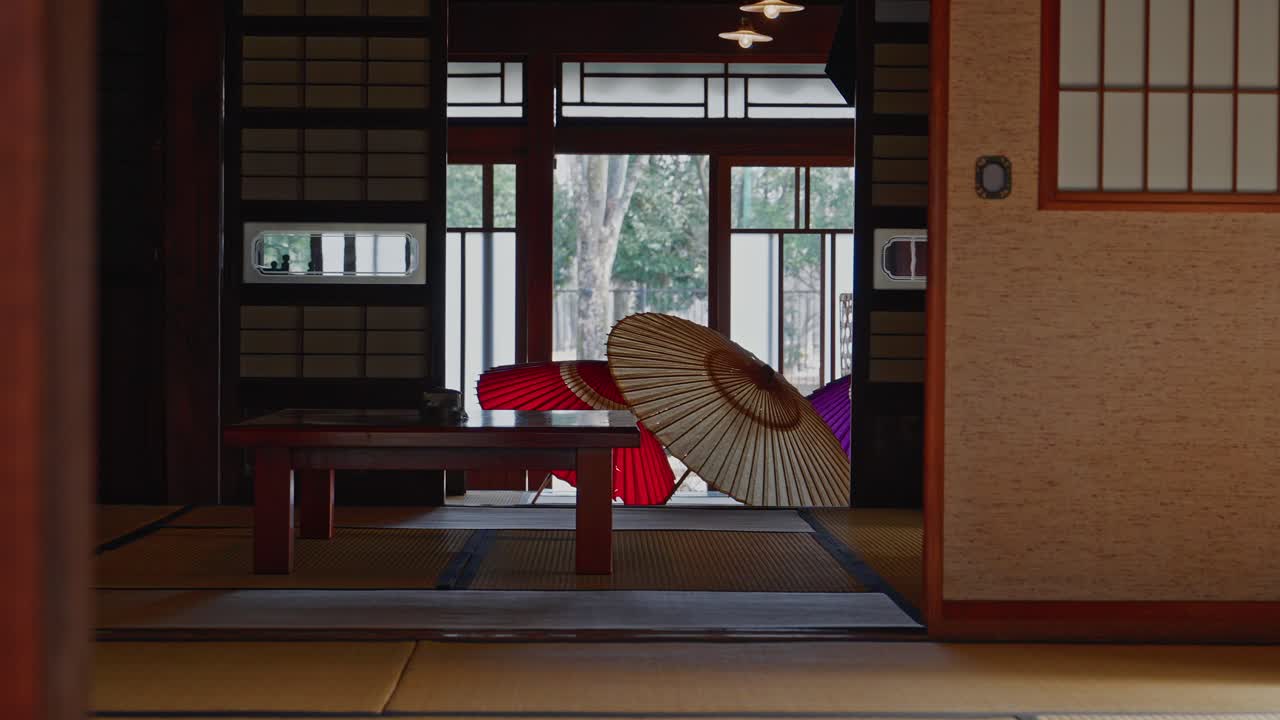 Elegantní interiér historického washitsu s výraznými červenými a fialovými tradičními olejovými papírovými deštníky (Wagasa) vystavenými na tatami podlaze.