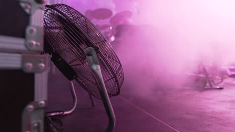 close-up of a fan on a stage with fog and a blurred band in the background