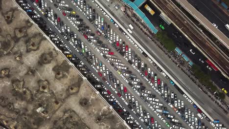 Toma-Aérea-Giratoria-De-Un-Estacionamiento-Congestionado,-Entre-Una-Carretera-Principal-Cubierta-De-Tráfico-Y-Un-Páramo-Vacío,-Bangkok,-Tailandia