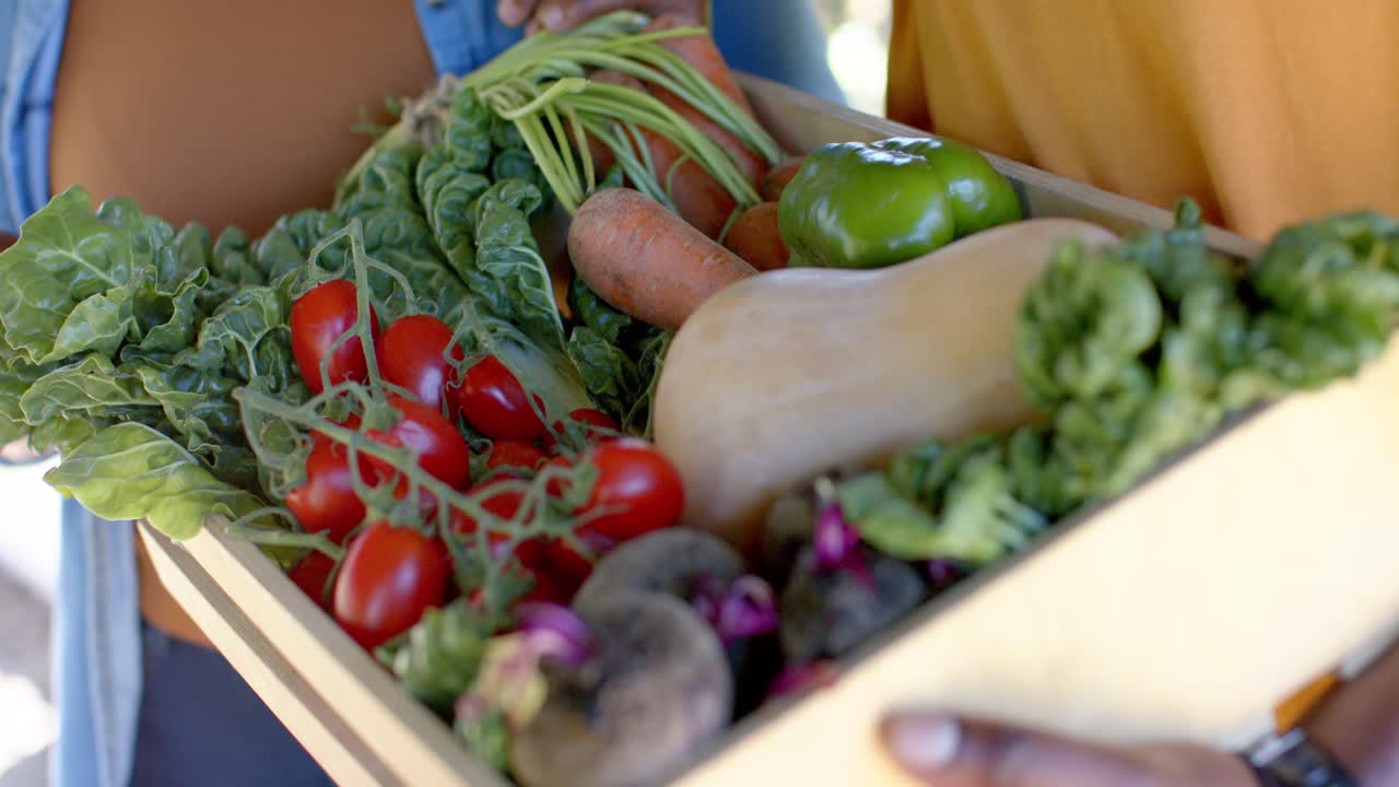Caixa de vegetais frescos inclinando-se enquanto as mãos dos seguradores se movem, revelando os produtos para exposição no mercado.