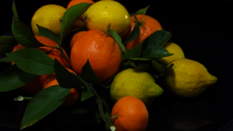 citrus fruits, yellow lemons and orange mandarins rotating on black background, healthy food