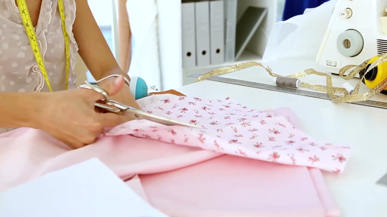 Designer cutting pink cloth with scissors