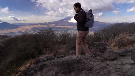 male hiker sitting down on top of mountain for break, mt fuji in background