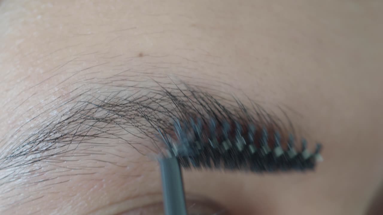 Close-up of a woman's eyebrow being brushed with a makeup brush