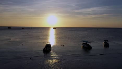 Drone-aerial-sunset-shot-with-camera-moving-past-palm-tree-towards-the-ocean-and-sun-on-Koh-Tao,-Thailand