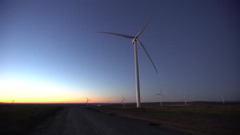 wind turbines at dawn next to gravel road