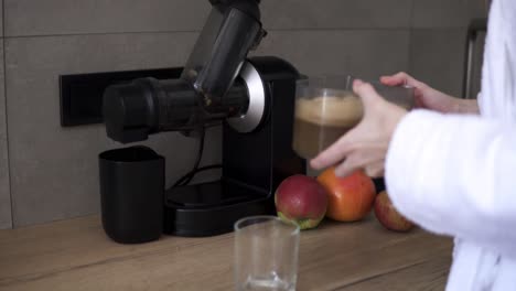 Woman-made-apple-juice-using-juicer,-pouring-fresh-juice-into-glass