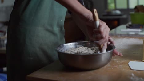 mezcla de masa completamente levantada arrancada de un cuenco de acero usando una cuchara de hornear, filmada como un disparo de cámara lenta de primer plano medio