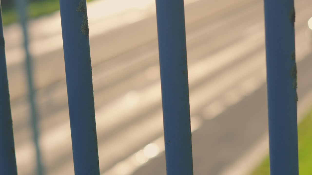 Out of focus cars driving on multi lane highway through metal bars. Perfect for projects focusing on logistics, daily commutes, automotive technology