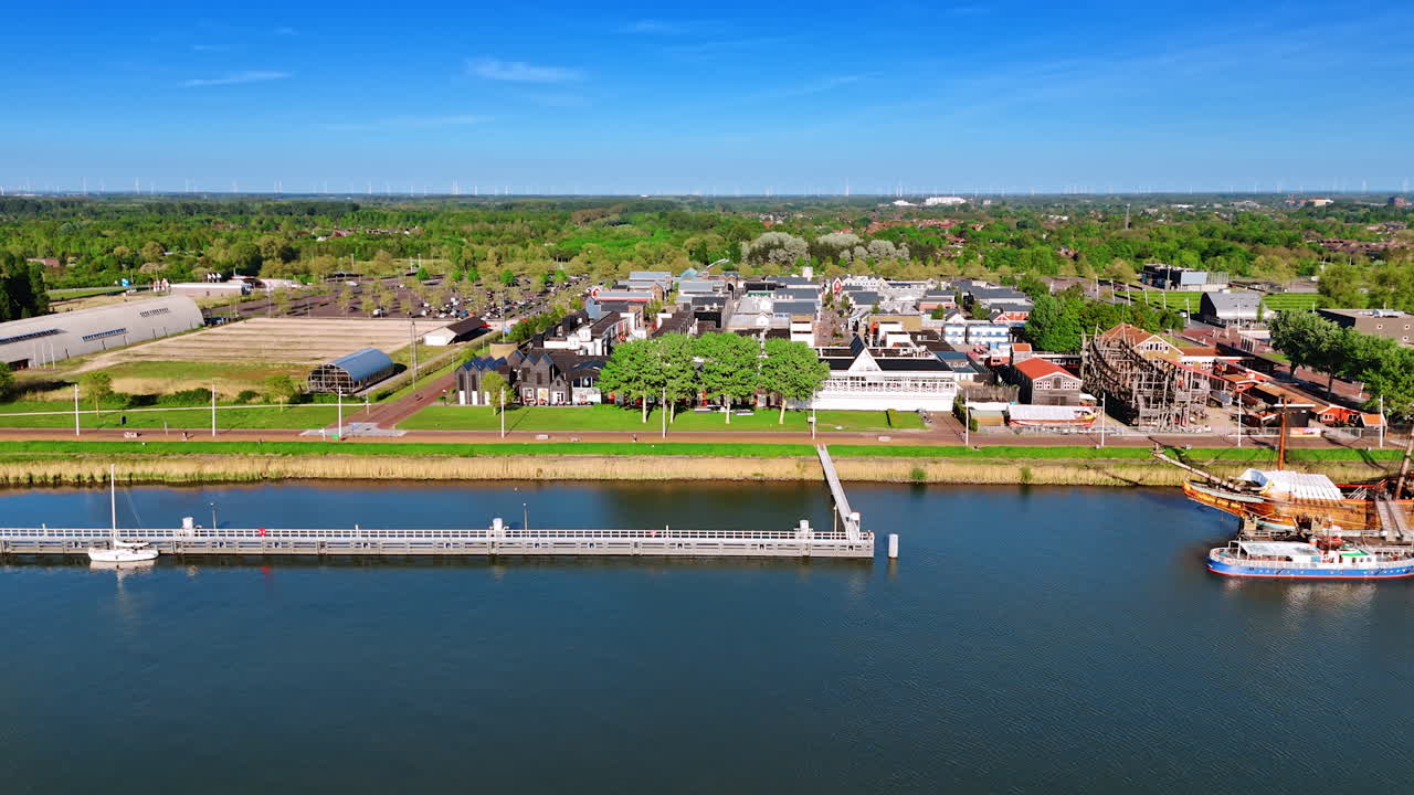 Lovely picturesque green waterfront of lake Markermeer in Lelystad, the Netherlands. View on the old ship reconstruction in the museum Batavialand.