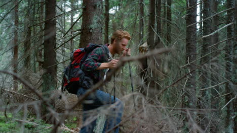 smiling guy trekking woods in summer time. happy traveler hiking in green forest