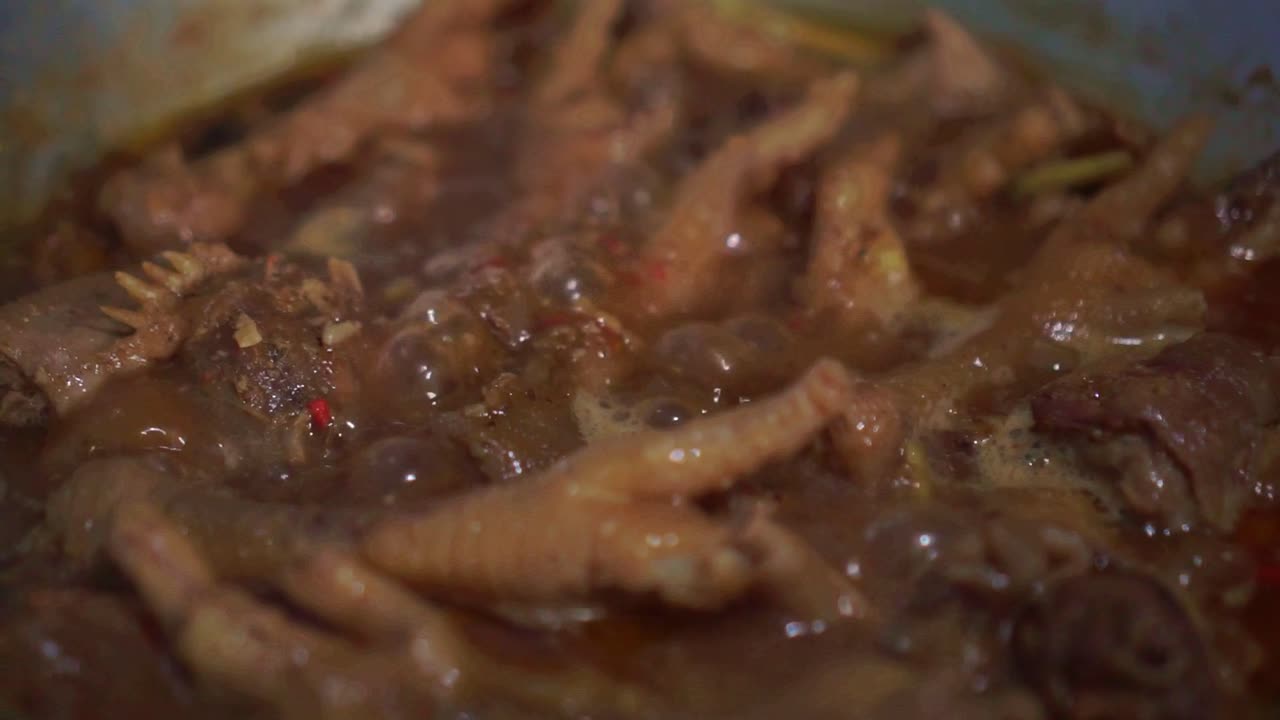 Pezzi di pollo teneri che bollono in un sugo saporito. Scena di cucina ravvicinata con una ricca consistenza della salsa