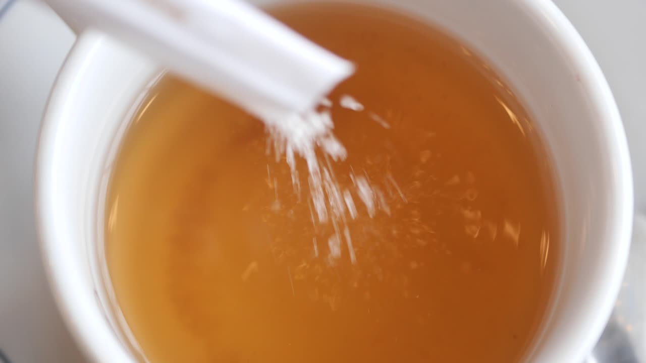 Una tazza di tè con zucchero e un cucchiaino
