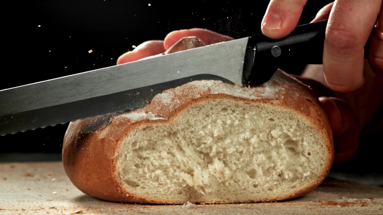 Slow Motion of a Hand Slicing Freshly Baked Bread