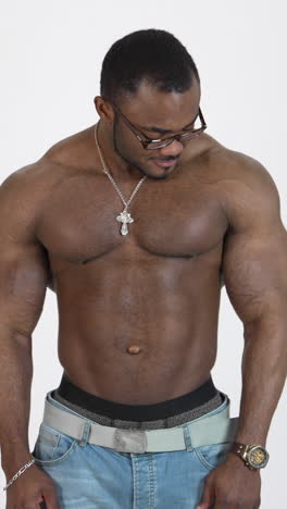 portrait of shirtless afro american sportsman. smiling man with trained body moving his pectoral muscles. black sportsman showing his muscular body on camera in studio. vertical video