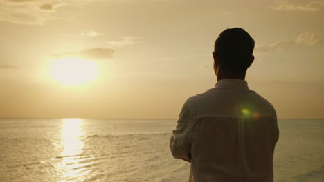 lonely man looking forward to the sunset over the sea back view romance and vacation at sea