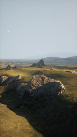 grassy field with rocks and mountains