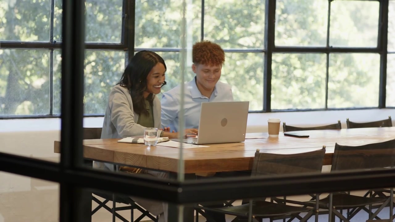 Woman and man on laptop, high-fiving after finance win, charts overlaying, reviewing, woman leaving