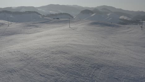 una persona sospechosa se acerca a un auto en una colina nevada
