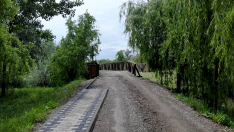 dirt road with willow trees towards the wooden bridge