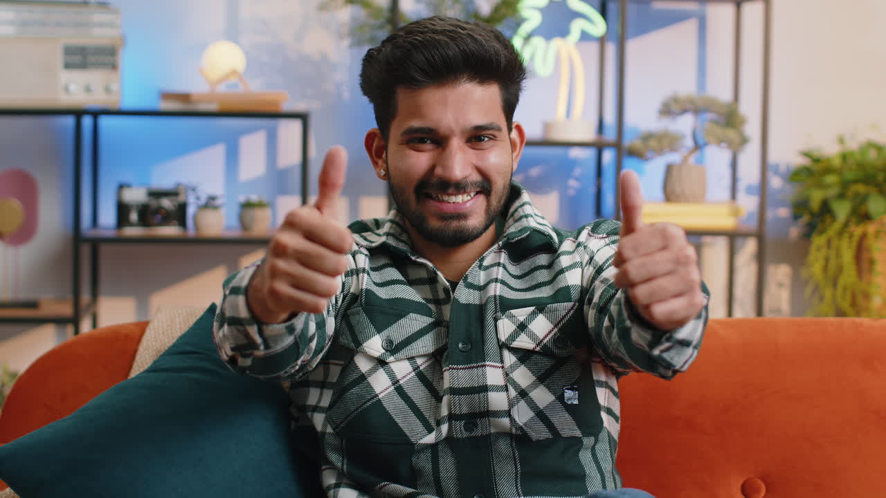 Happy indian man looking approvingly at camera showing thumbs up like positive sign good news