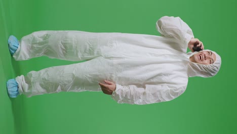 full body of asian male scientist talking on smartphone while standing on green screen background