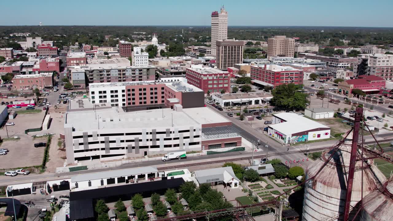 4K drone footage of Magnolia Silos in downtown Waco, Texas, showing the famous landmark, surrounding buildings, and lively city atmosphere under a clear sky