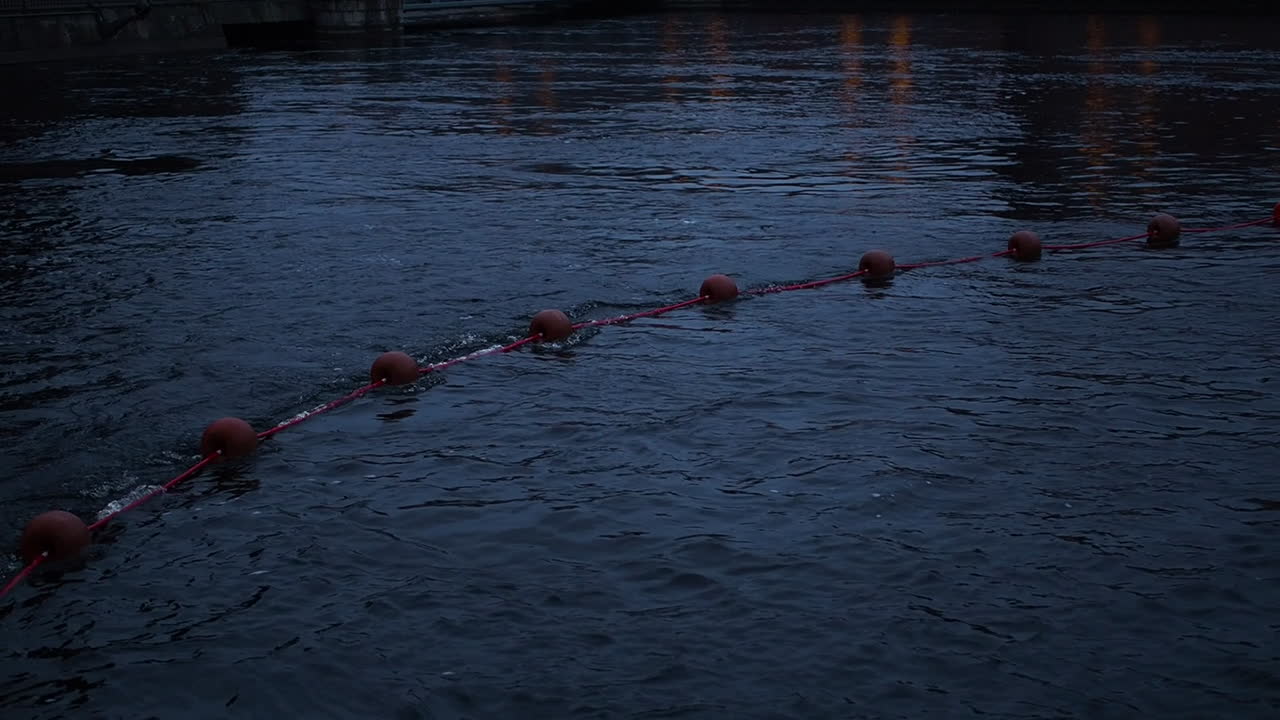 cuerda con boyas rojas flotando en el río por la noche