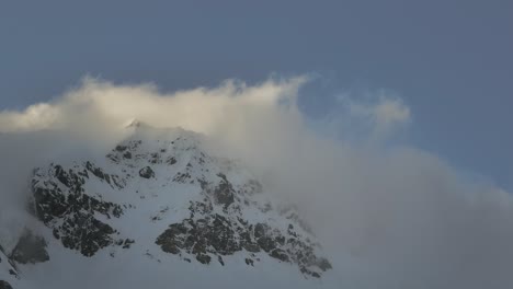 Clouds-rolling-over-snowy-mountain-ridge,-New-Zealand