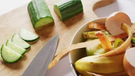 video de cuchillo y pepino en la tabla de cortar, con residuos orgánicos en el contenedor de compostaje de la cocina