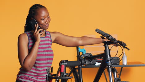 Ingeniero-Alegre-En-El-Trabajo-Tomando-Un-Descanso-De-La-Reparación-De-Bicicletas,-Hablando-Por-Teléfono