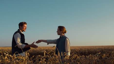 Agro partners shaking hands inspect cultivated wheat harvest in golden sunlight