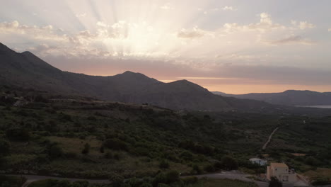 Aerial-Truck-Shot-of-Landscape-and-Mountains-in-Crete,-Greece-at-Sunset-with-Sun-Flares-and-Warm-Colours