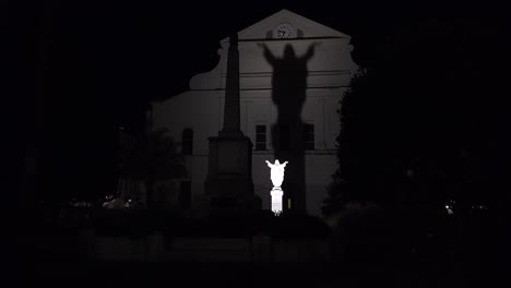 a statue of jesus is made large in shadow at night on st louis church in jackson square new orleans