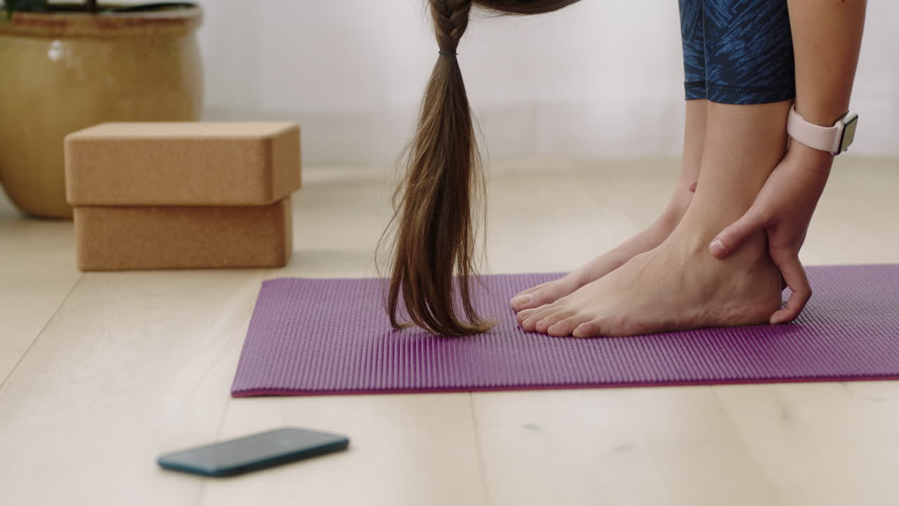 atractiva mujer de yoga ejercitando un estilo de vida saludable practicando pose de flexión hacia adelante disfrutando del entrenamiento en casa entrenando en una colchoneta de ejercicios